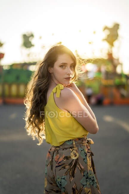 Female standing looking at camera at fairground and enjoying summer weekend during sunset — Stock Photo