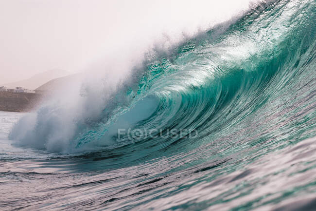 Могутні піняві морські хвилі котяться і бризкають над поверхнею води проти блакитного неба. — стокове фото