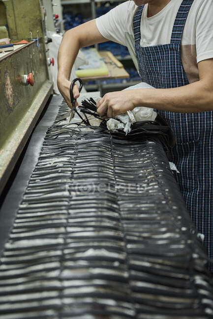 Рабочий снимает левую ткань после процесса резки на китайской обувной фабрике — стоковое фото