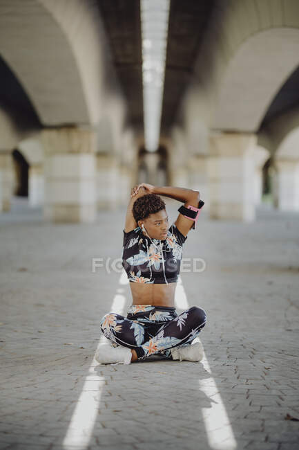 Giovane donna afro-americana fitness che allunga le braccia prima di correre sulla strada della città — Foto stock