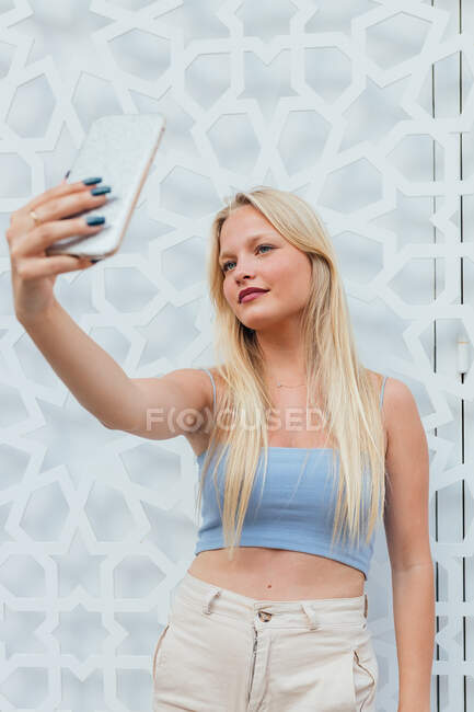 Femme blonde aux cheveux blonds se faisant tirer dessus sur un téléphone portable dans la rue de la ville — Photo de stock