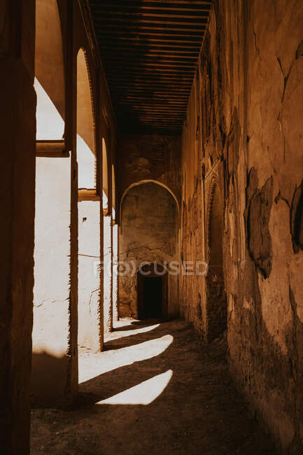 Fachada de edificio islámico con arco en mal estado con puerta abierta en el día soleado en la calle de Marrakech, Marruecos - foto de stock