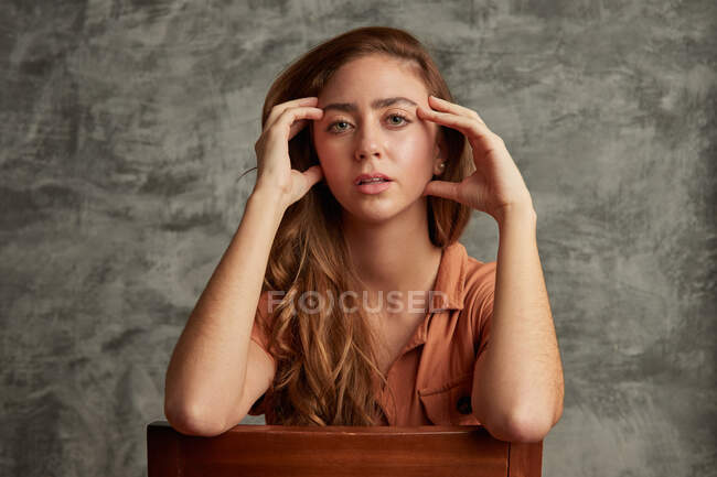 Mulher atraente com cabelos longos olhando para a câmera em fundo cinza em estúdio — Fotografia de Stock