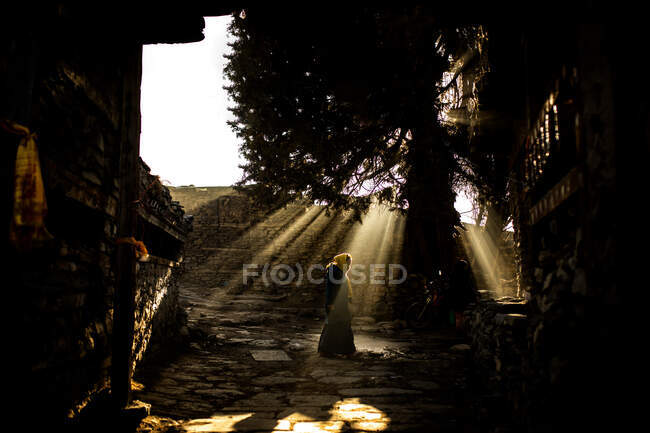 Side view of unrecognizable female standing in garden near Buddhist temple on sunny day in Nepal — Stock Photo