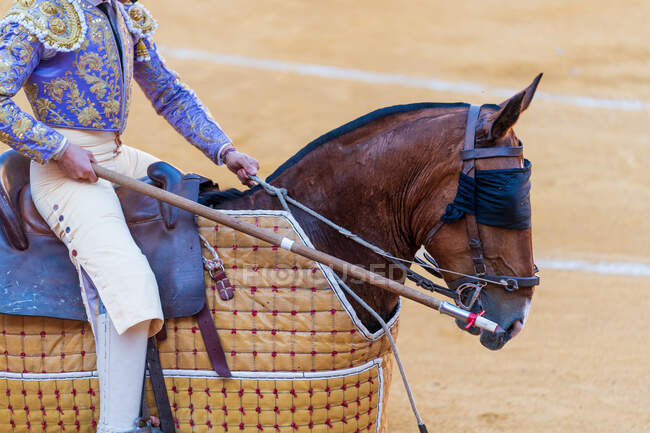 Crop of unrecognizable picador with lance riding horse during corrida — Stock Photo