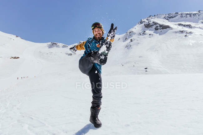Content male athlete in sports clothes having fun with raised leg while looking at camera against Sierra Nevada in Spain — Stock Photo