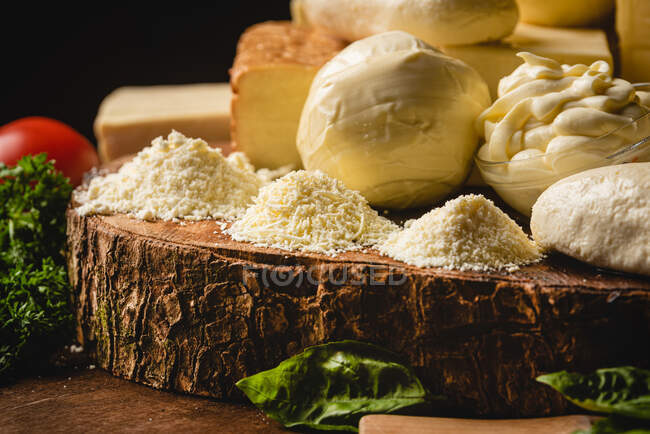 Colección de queso italiano sobre mesa con verduras frescas y perejil rizado con hojas de albahaca sobre espátulas - foto de stock