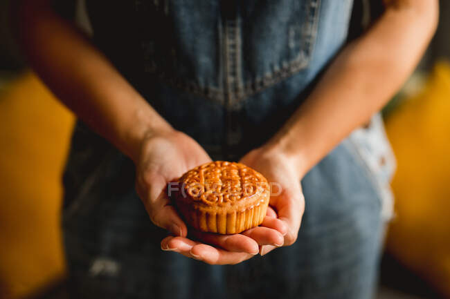 Unrecognizable female showing tradition Chinese mooncake to camera against blurred background — Stock Photo