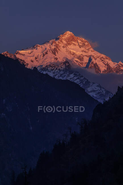 Montanhas rochosas do Himalaia cobertas de neve iluminada por luz laranja brilhante no Nepal — Fotografia de Stock