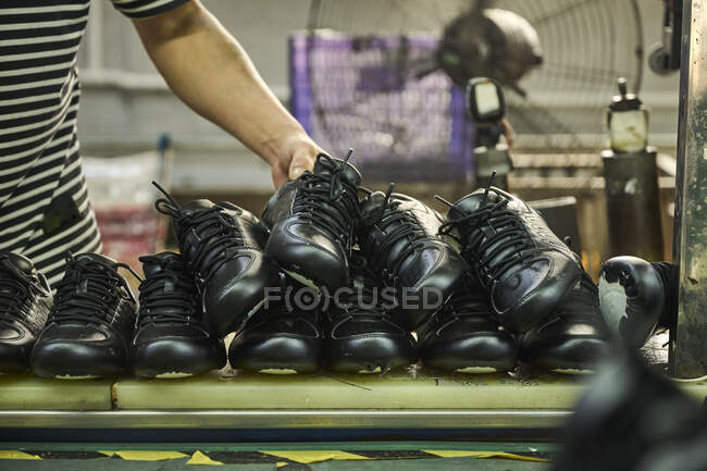 Dettaglio delle mani dell'uomo mentre controlla le scarpe nella linea di produzione di controllo di qualità nella fabbrica di scarpe cinese — Foto stock