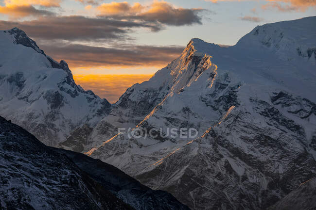 Montagne rocciose dell'Himalaya coperte di neve con luce arancio brillante del tramonto in Nepal — Foto stock