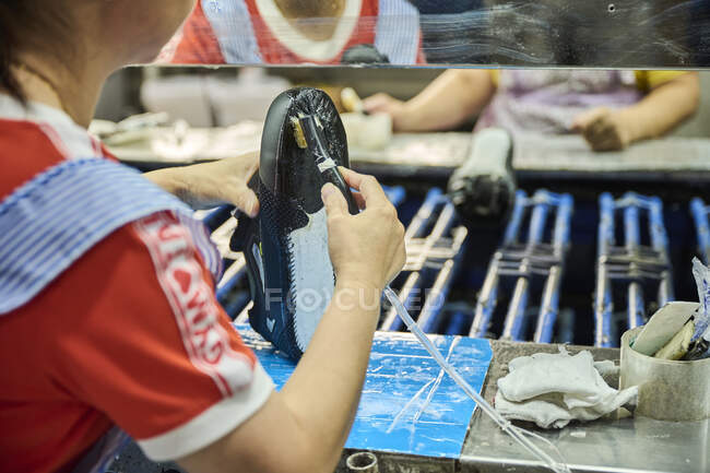 Detail des Arbeiters, der Kleber auf die Schuhsohle in einer Produktionslinie der chinesischen Schuhfabrik aufträgt — Stockfoto
