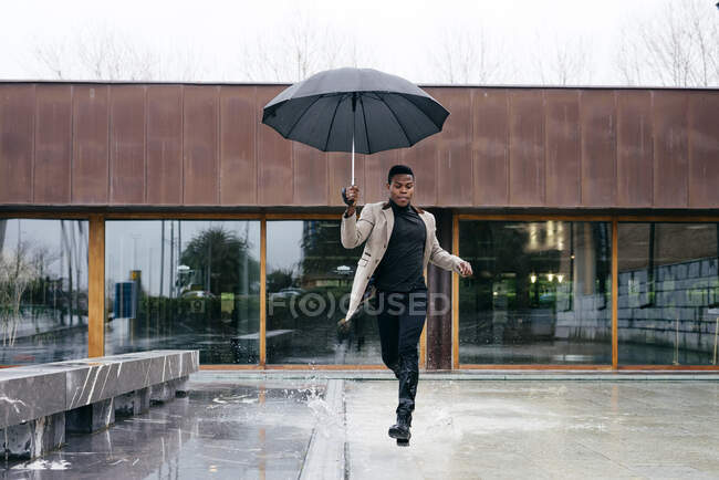 Портрет елегантного чорного чоловіка з сірим пальто і парасолькою на вулиці — стокове фото