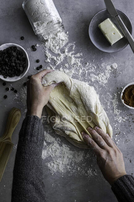 Сверху рука неузнаваемой женщины катит свежее тесто для выпечки на уютной кухне — стоковое фото