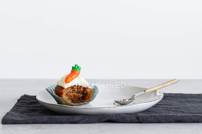 Cupcake di carote mezzo mangiato con crema su piatto su sfondo bianco — Foto stock