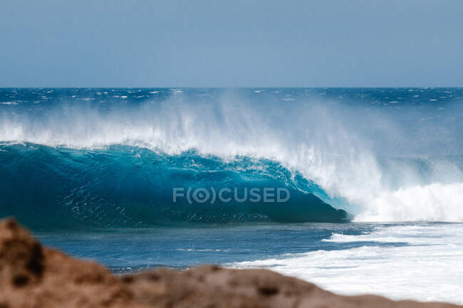 Потужні пінисті морські хвилі котиться і бризкає над поверхнею води на блакитне небо — стокове фото