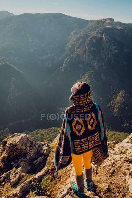 Обратный вид на неузнаваемую беззаботную женщину-исследователя, стоящую в горах и наслаждающуюся свободой — стоковое фото