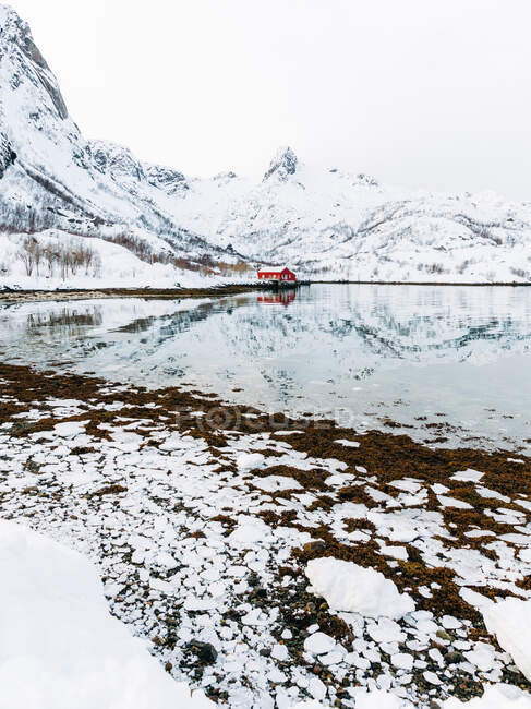 Red cabin located on mountain range snowy sea coast on Lofoten Islands, Norway — Stock Photo