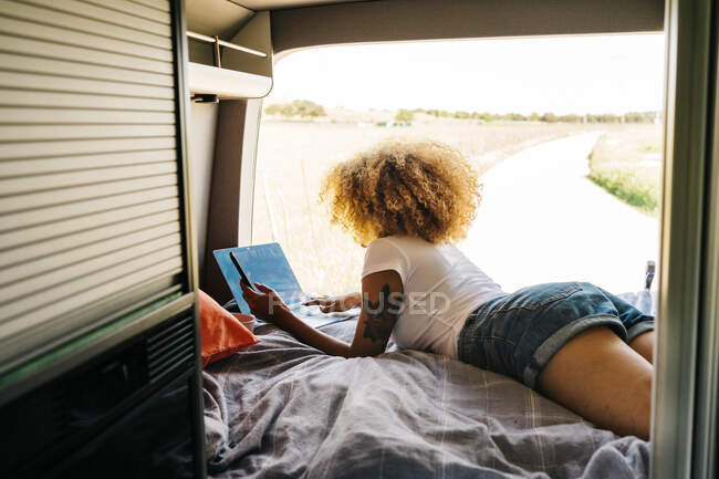 Молода афроамериканська мандрівниця з кучерявим волоссям працює на ноутбуці під час літніх канікул. — стокове фото