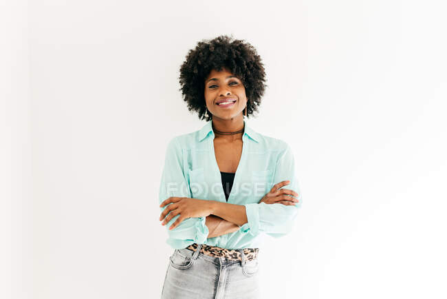 Happy young African American female with beautiful afro hair in trendy outfit having on white background — Stock Photo