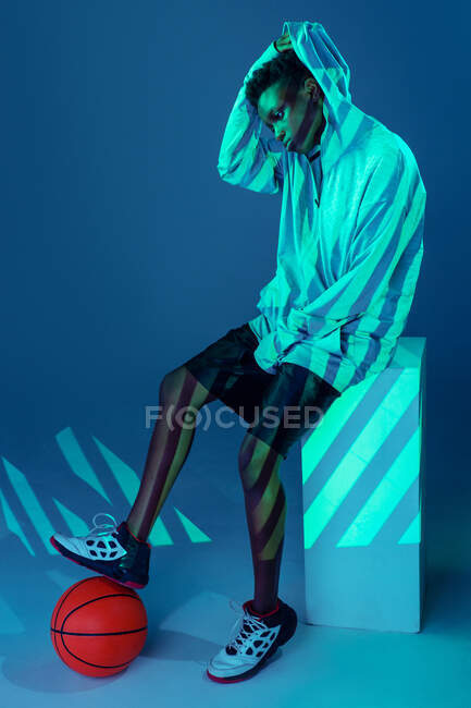 Чорна жінка зі спортивним вбранням в студії, освітлені гелями та проекторними вогнями — стокове фото