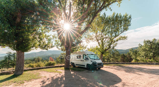 Путешествующий кемпер припаркован на асфальтовой дороге в лесу в солнечный день летом — стоковое фото