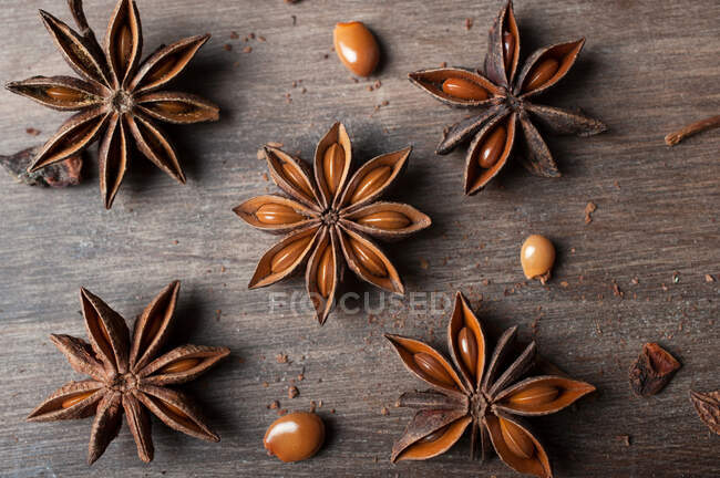 Крупним планом ароматичні висушені зірки анісу з насінням, розкиданими на сільському дерев'яному столі для гастрономічного концепту фону — стокове фото