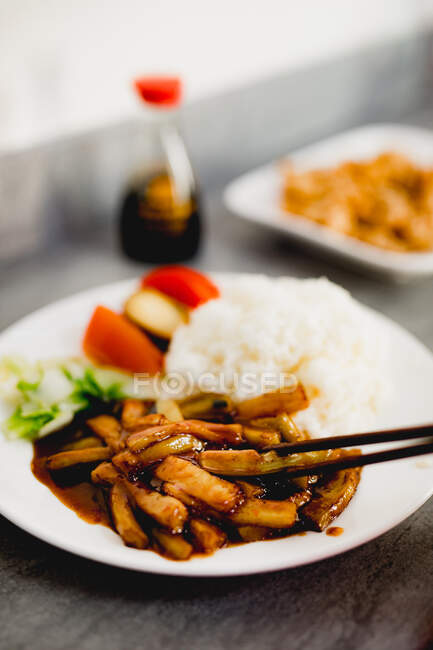 Apetitivo cocido berenjena Yuxiang con verduras saludables y arroz en plato blanco en el restaurante asiático - foto de stock