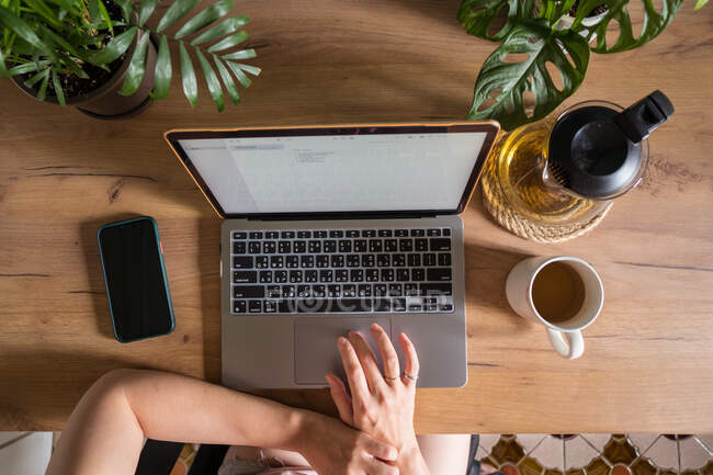 Visão superior da colheita freelancer feminino irreconhecível digitando no laptop enquanto sentado à mesa durante o trabalho remoto — Fotografia de Stock