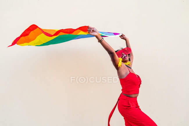 Stylish African American female in trendy clothes and glasses with colorful flag looking away during celebration — Stock Photo