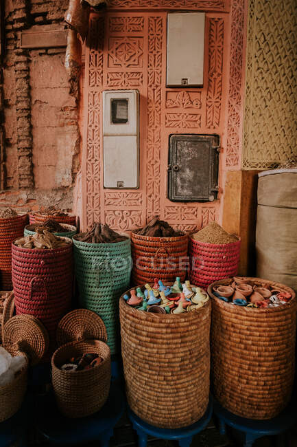 Плетеные корзины с различными керамическими изделиями размещены снаружи декоративного здания на уличном рынке в Марракеше, Марокко — стоковое фото