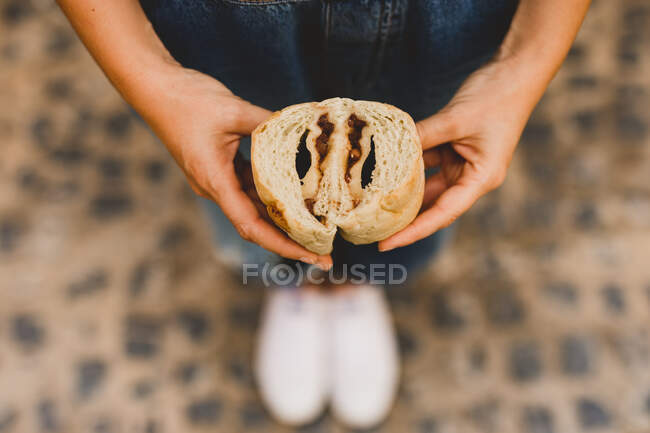De cima as mãos da mulher que mantém o pão azuki cozido no forno saboroso cortam na metade — Fotografia de Stock