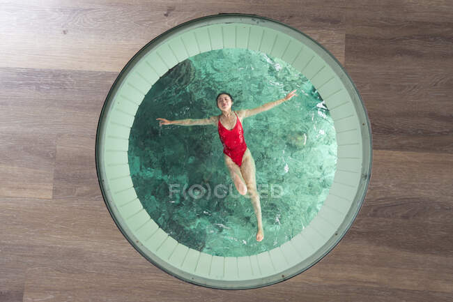 Overhead of Asian female with open arms and closed eyes in swimsuit relaxing in swimming pool in Maldives — Stock Photo