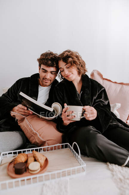 Ângulo alto de casal gentil relaxando na cama juntos enquanto tomam café da manhã — Fotografia de Stock