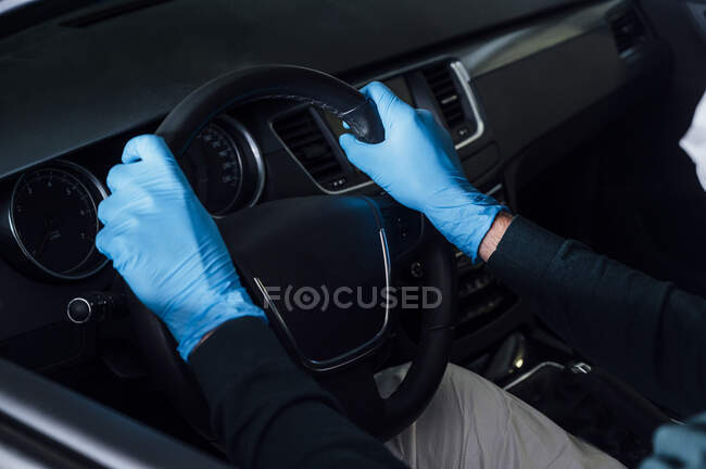 Vista laterale dell'uomo irriconoscibile ritagliato che utilizza una maschera protettiva che guida l'auto durante la quarantena — Foto stock