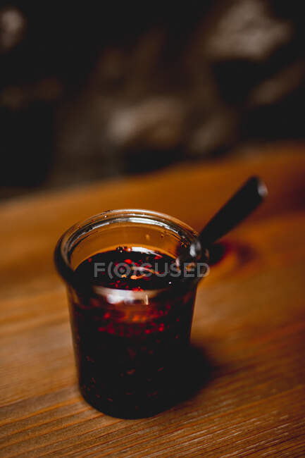 Glass of spicy chili sauce on wooden table — Stock Photo