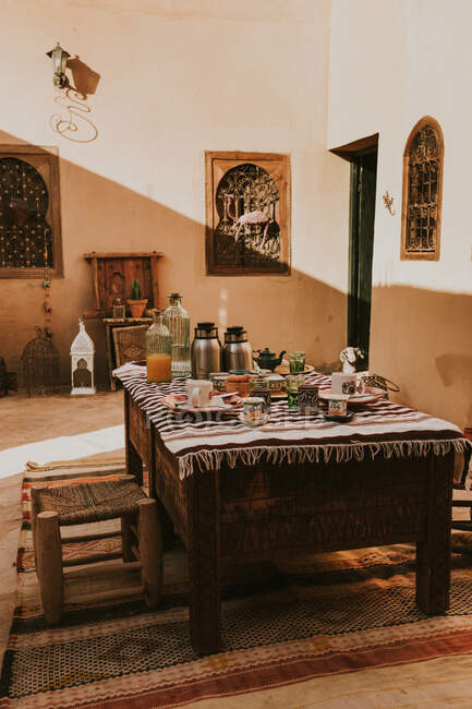 Tavolo in legno con cibi e bevande situato nel cortile della tradizionale casa islamica nella giornata di sole a Marrakech, Marocco — Foto stock