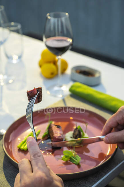 Mãos segurando talheres onwell enfeitado grelhado prato de lombo de carne no restaurante de alta cozinha ao ar livre — Fotografia de Stock