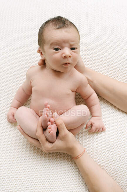 From above of cropped unrecognizable loving mother looking at adorable naked infant on bed at home — Stock Photo