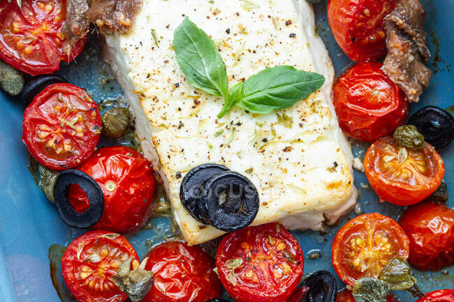 Gros plan de tomates cerises mûres avec tranches d'olive noires et fromage feta dans un plat de cuisson près de penne non cuit — Photo de stock
