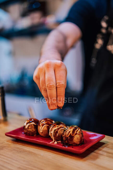 Faceless chef pouring with spices rounds of meat with sauce on stylish plate in ramen bar — Stock Photo