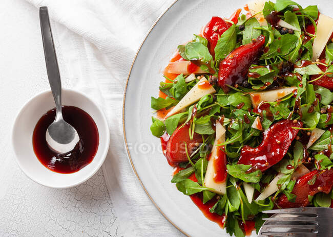 Верхній вид смачного салату з аругулою і айсом подається на тарілці з соусом на столі. — стокове фото