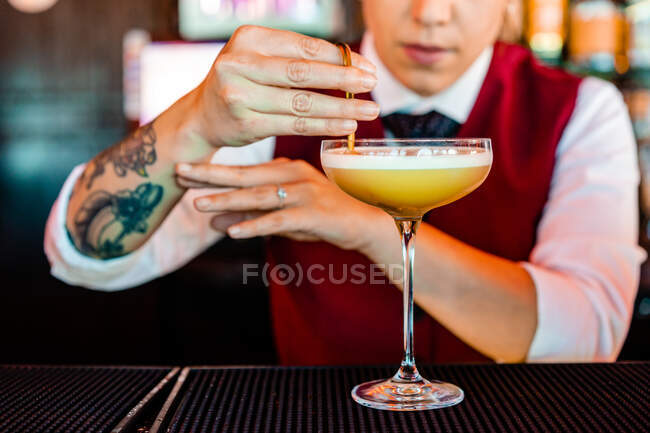 Anónimo profesional joven camarera decorar con un palo mientras se prepara cóctel agrio en el bar - foto de stock