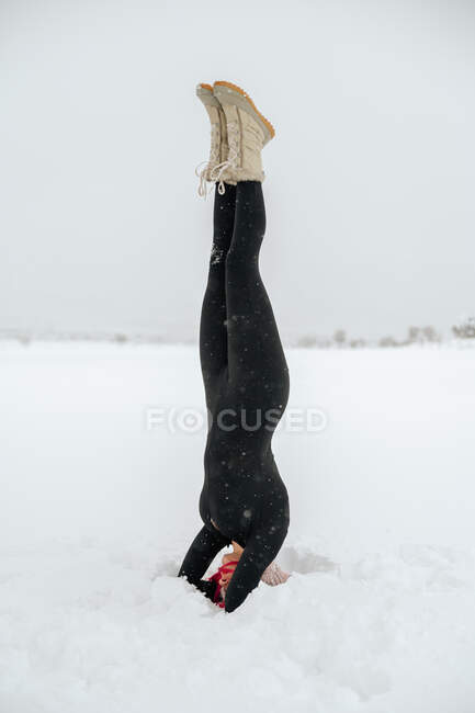 Adatto equilibrio femminile a Salamba Shirshasana sul prato innevato durante lo yoga in inverno — Foto stock
