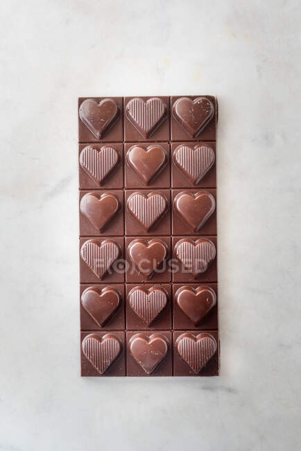 Vista dall'alto di deliziose caramelle al cioccolato con noci a forma di cuore su sfondo tavolo di marmo — Foto stock