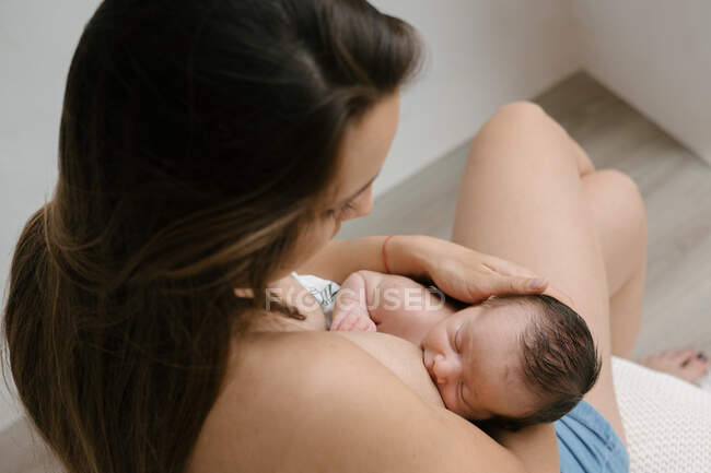 Обрізаний невпізнаваний люблячої матері грудного вигодовування новонародженого, сидячи в кімнаті вдома — стокове фото