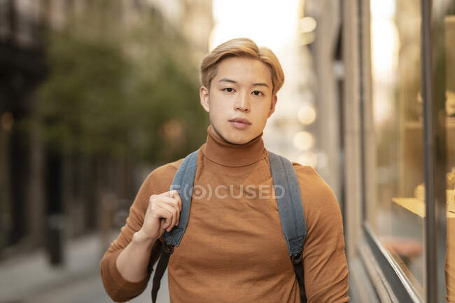 Впевнена етнічна чоловіча модель з світлим волоссям і в модному черепашці, що стоїть в місті і дивиться на камеру — стокове фото