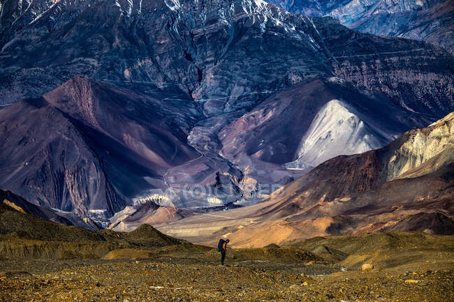 Далекий вид туриста стоїть на скелястій землі на тлі нерівного гірського хребта Гімалаї в Непалі. — стокове фото