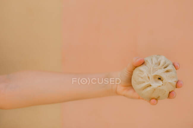 Mãos de meia idade segurando baozi cozido no vapor contra fundo liso — Fotografia de Stock