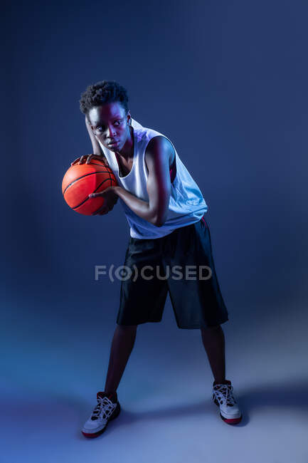 Чорна жінка з баскетбольним вбранням в студії з використанням кольорових гелів і проекторних вогнів — стокове фото